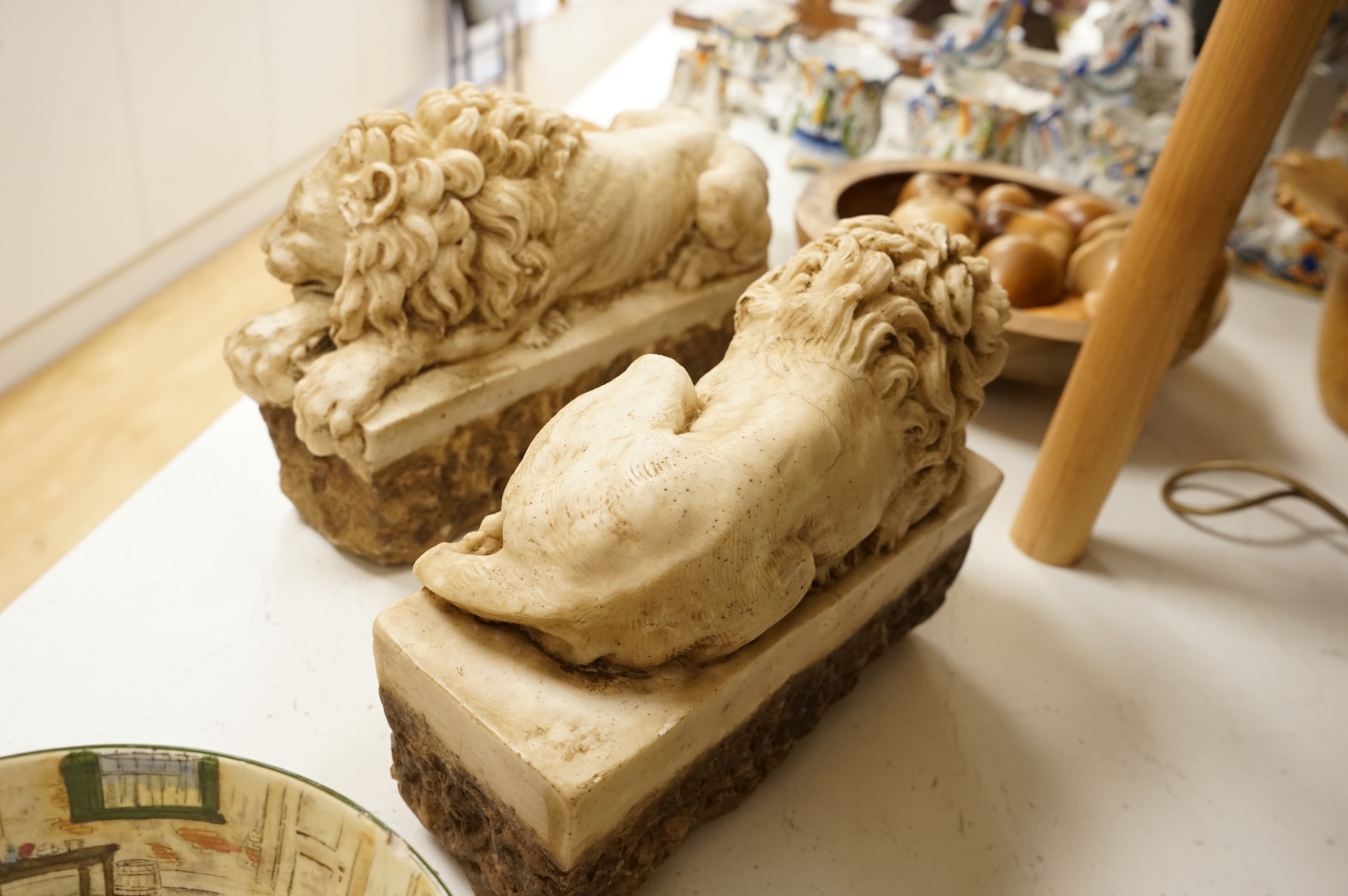 A pair of 20th century faux marble models of recumbent lions, 31cm